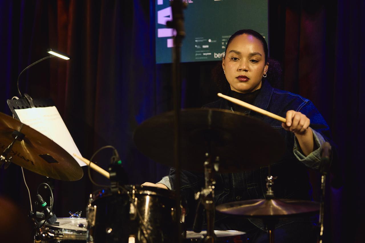 Eine junge Frau sitzt am Schlagzeug und ist fast träumerisch vertieft in ihr Spiel