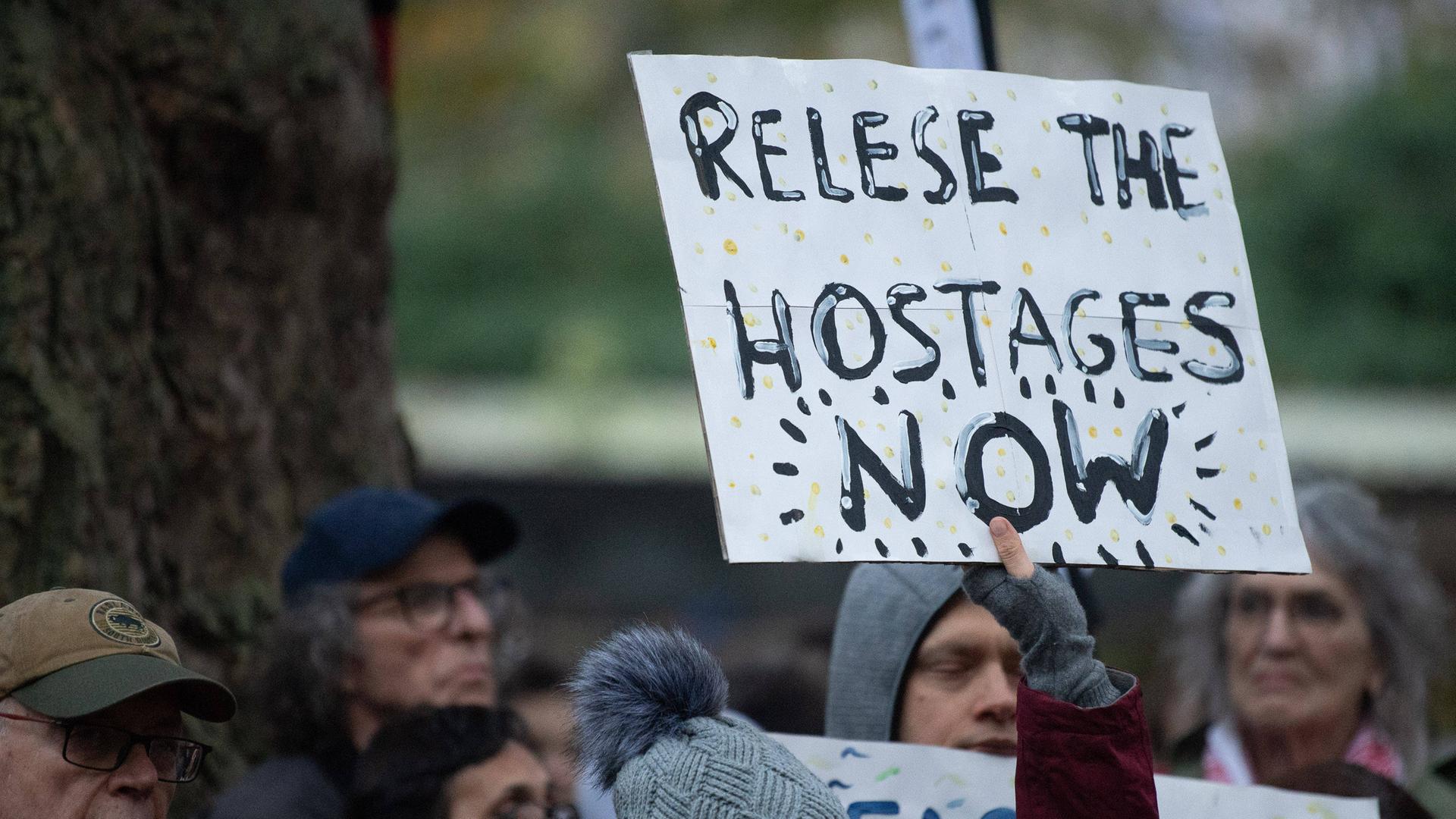 Eine Demonstrantin hält ein Schild hoch mit der Aufschrift: "Release the hostages now".