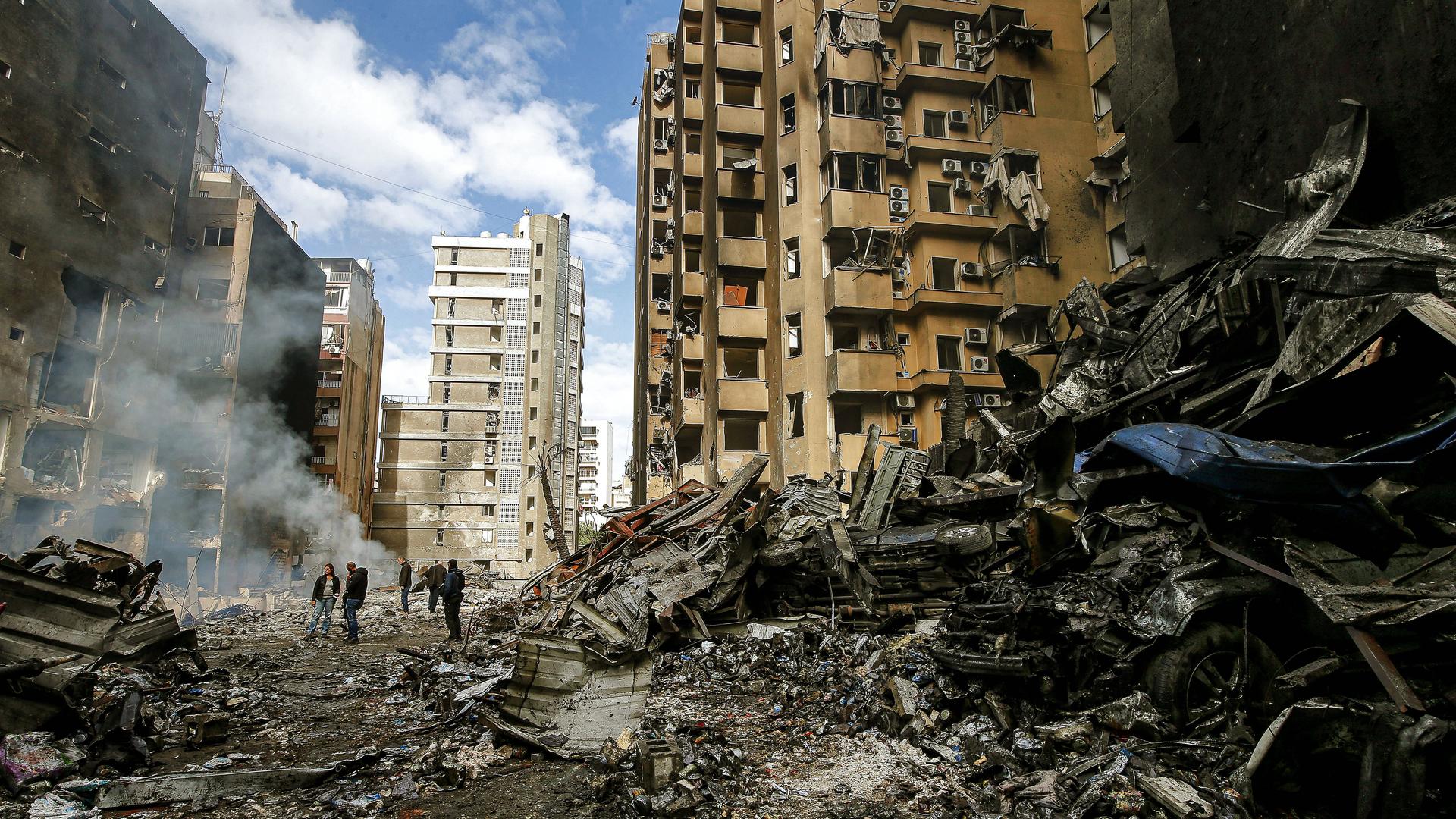 Menschen gucken auf die Schäden an Häusern in Beirut. 