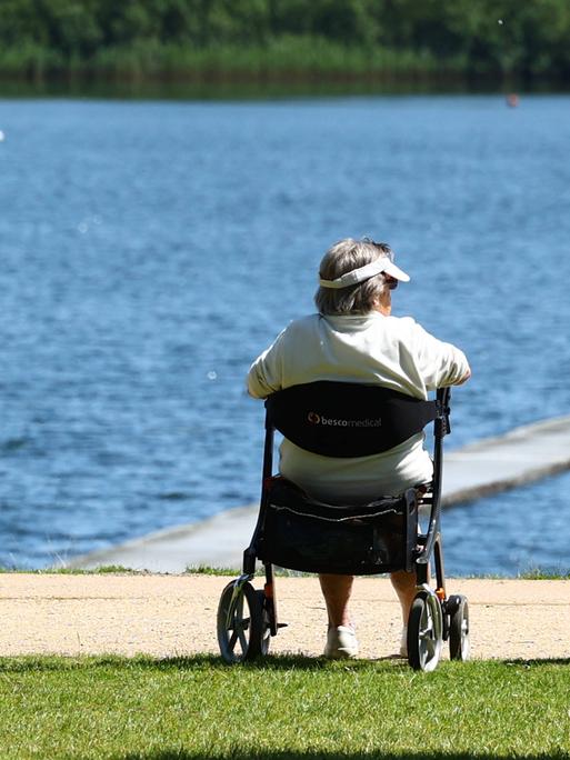 Rentner sitzt auf einem Gehwagen (Rollator) an einem Seeufer in Hamburg
