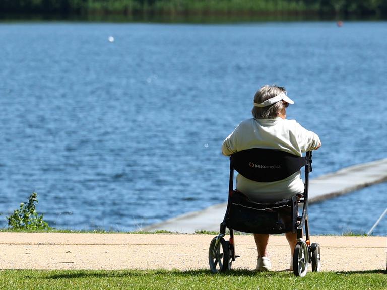 Rentner sitzt auf einem Gehwagen (Rollator) an einem Seeufer in Hamburg
