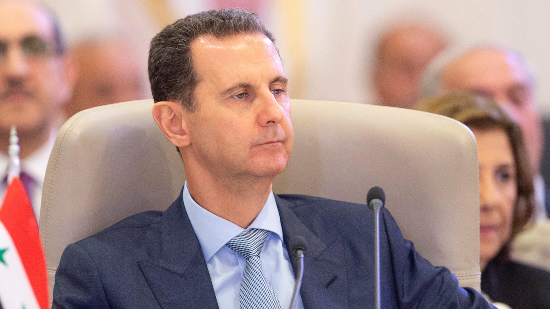 Syriens Präsident Baschar al-Assad sitz an einem Rednerpult.