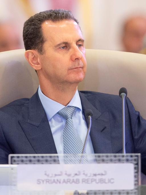 Syriens Präsident Assad sitzt an einem Rednerpult.