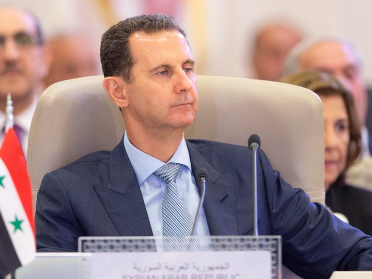Syriens Präsident Assad sitzt an einem Rednerpult.