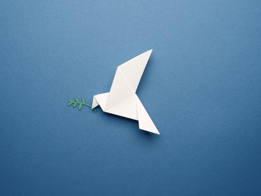 Weiße Origamitaube auf einem blauen Papierhintergrund