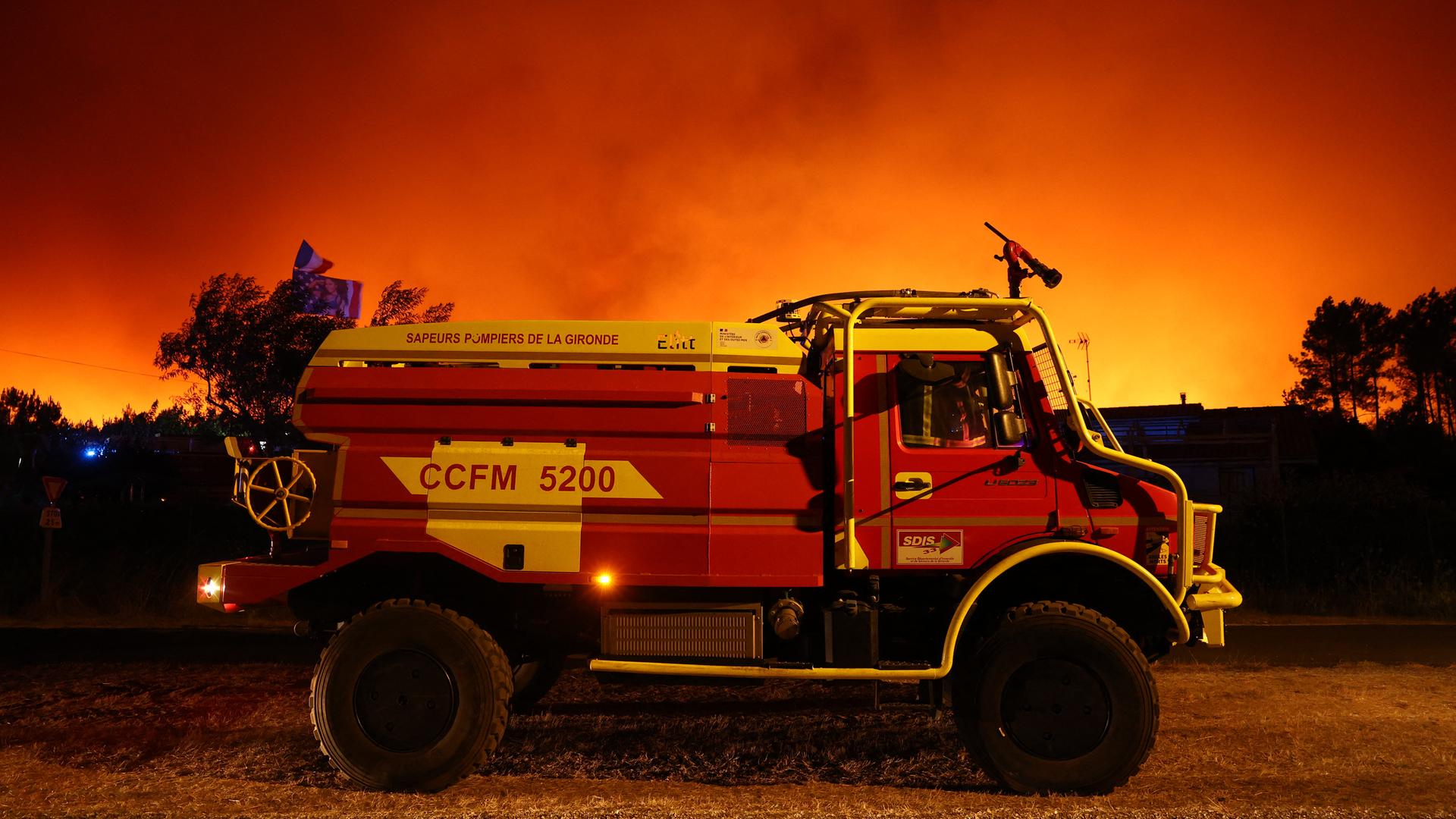 Das Foto zeigt ein Einsatzfahrzeug der Feuerwehr bei einem Waldbrand in Südwestfrankreich bei Le Porge.