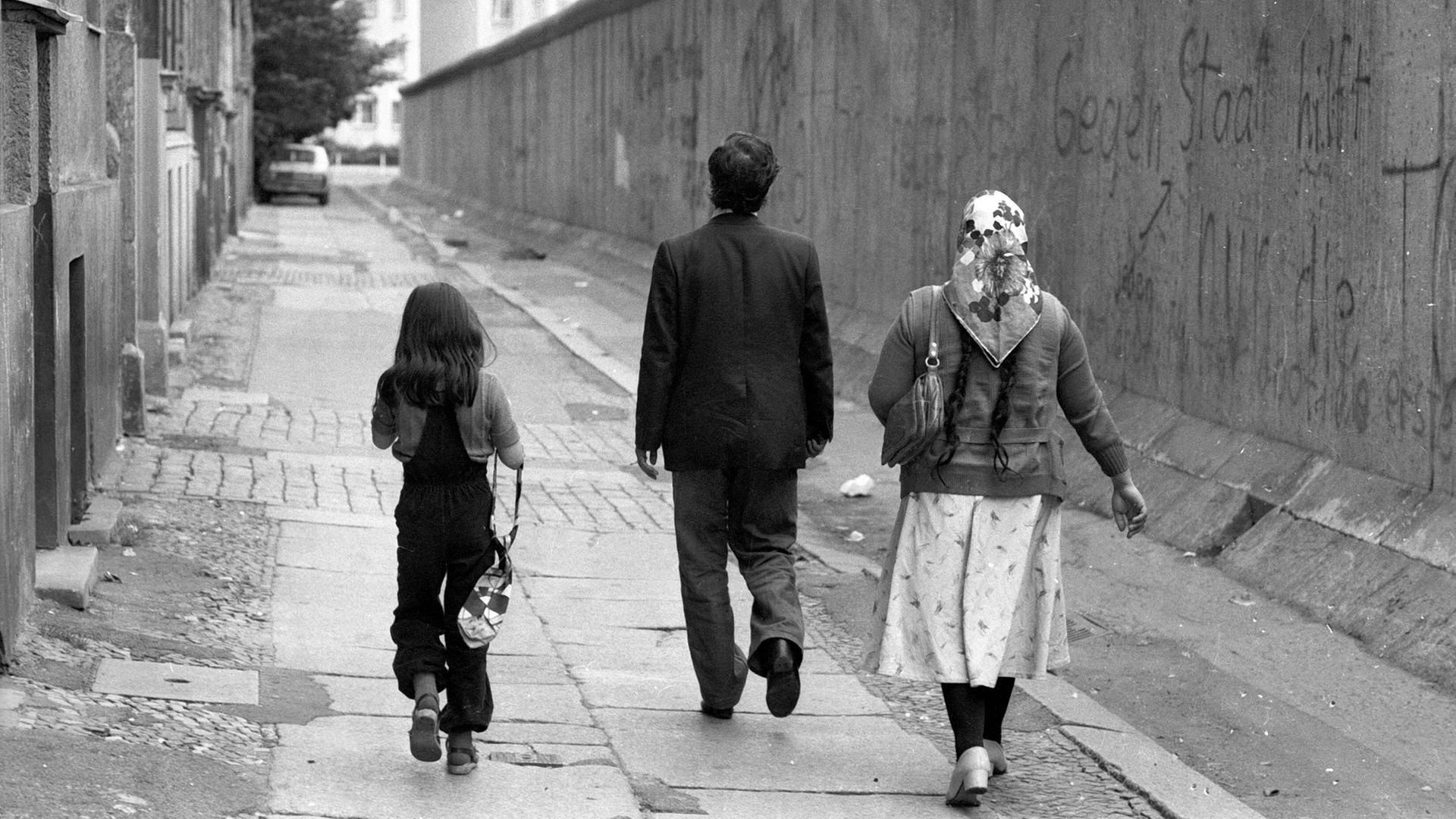 Eine türkische Familie geht entlang der Berliner Mauer spazieren.