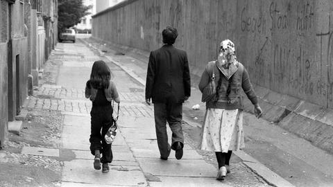 Eine türkische Familie geht entlang der Berliner Mauer spazieren.