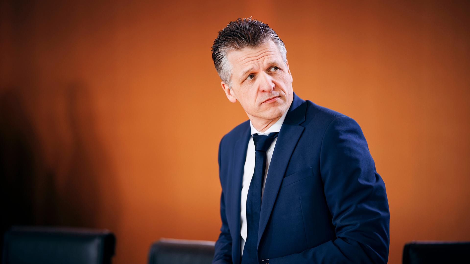 Thorsten Frei CDU, Chef des Bundeskanzleramtes, steht in blauem Anzug vor einer orangefarbenen Wand und schaut skeptisch über seine Schulter Thorsten Frei CDU, Chef des Bundeskanzleramtes, steht in blauem Anzug vor einer orangefarbenen Wand und schaut skeptisch über seine Schulter