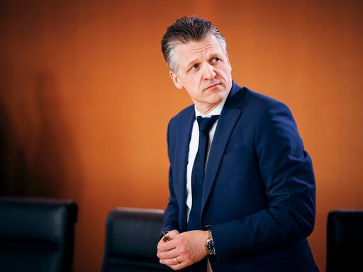 Thorsten Frei CDU, Chef des Bundeskanzleramtes, steht in blauem Anzug vor einer orangefarbenen Wand und schaut skeptisch über seine Schulter Thorsten Frei CDU, Chef des Bundeskanzleramtes, steht in blauem Anzug vor einer orangefarbenen Wand und schaut skeptisch über seine Schulter