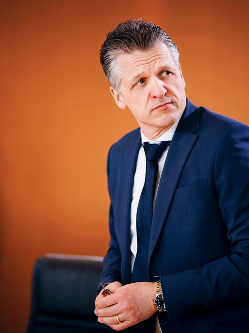 Thorsten Frei CDU, Chef des Bundeskanzleramtes, steht in blauem Anzug vor einer orangefarbenen Wand und schaut skeptisch über seine Schulter Thorsten Frei CDU, Chef des Bundeskanzleramtes, steht in blauem Anzug vor einer orangefarbenen Wand und schaut skeptisch über seine Schulter