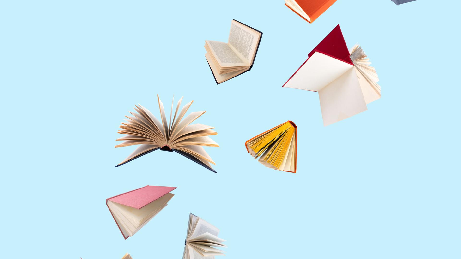 Farbenfroh bezogene Bücher fliegen vor einem blauen Hintergrund durch die Luft Farbenfroh bezogene Bücher fliegen vor einem blauen Hintergrund durch die Luft