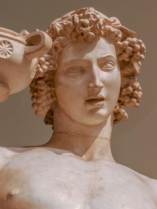Statue von Bacchus, der Haare aus Weintrauben hat und eine Schale in der Hand hält.