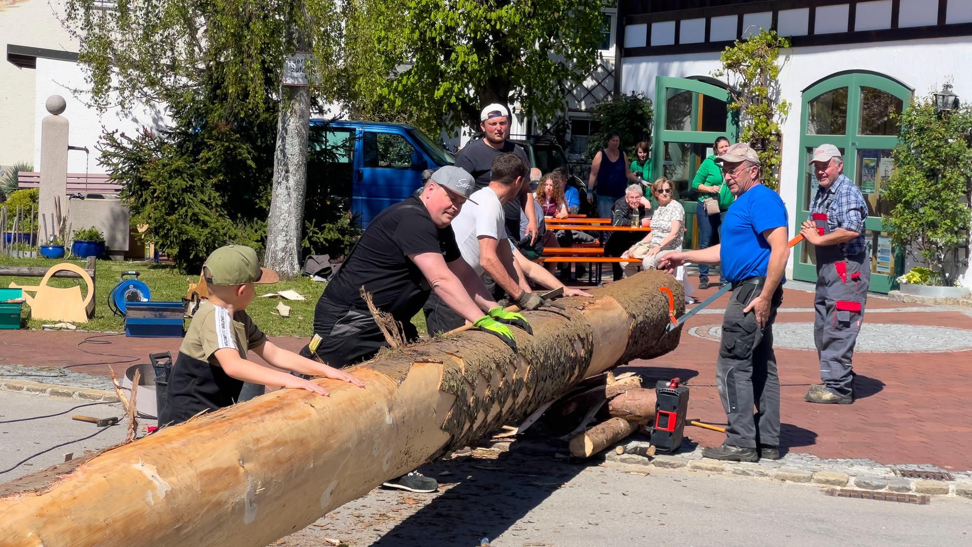 Menschen arbeiten an einem liegenden Maibaum. Menschen arbeiten an einem liegenden Maibaum.
