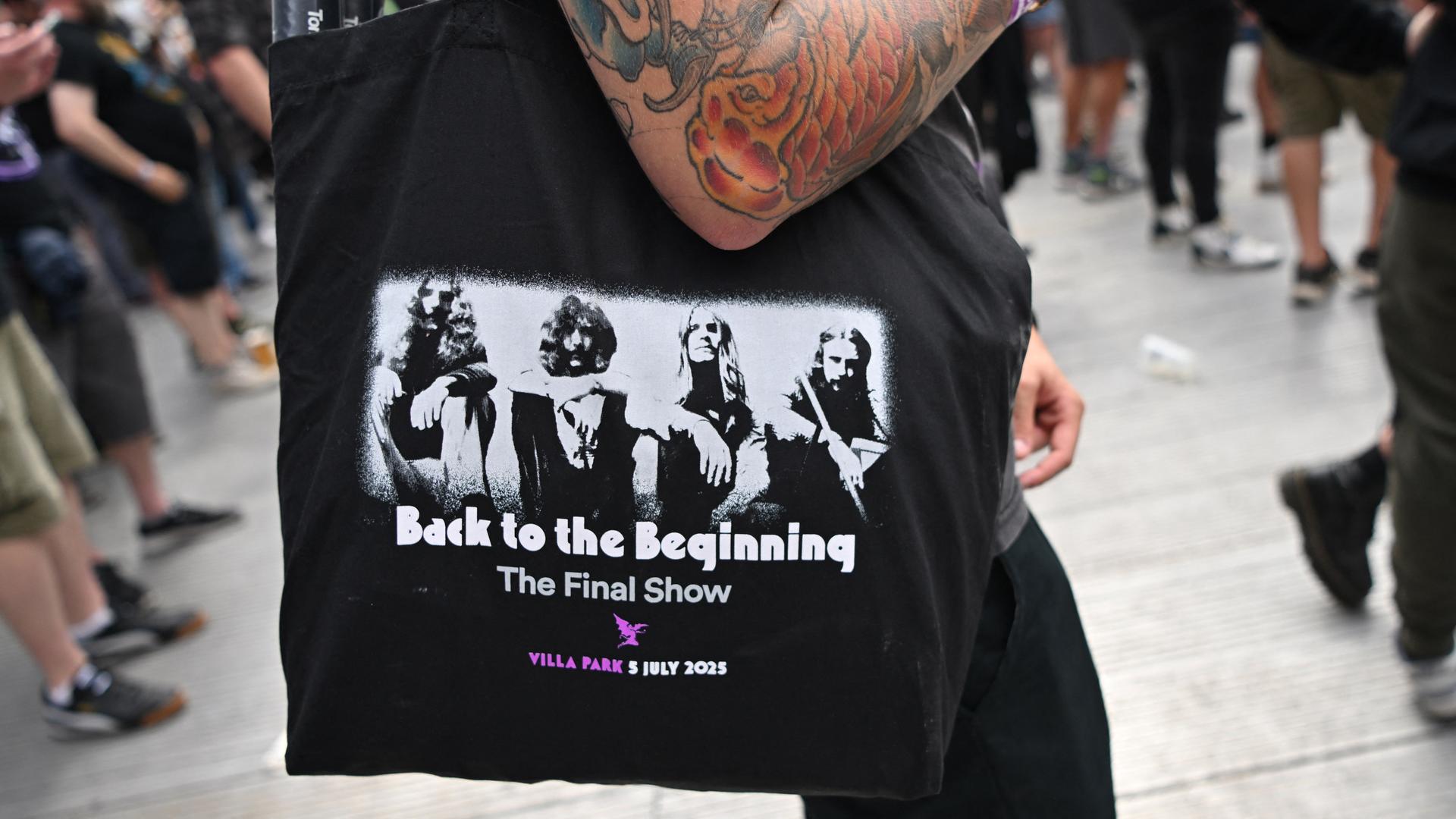 Ein Fan trägt eine Tasche mit dem Aufdruck von Black Sabbath aus der Gründungszeit und der Aufschrift "Back to the Beginning". Ein Fan trägt eine Tasche mit dem Aufdruck von Black Sabbath aus der Gründungszeit und der Aufschrift "Back to the Beginning".