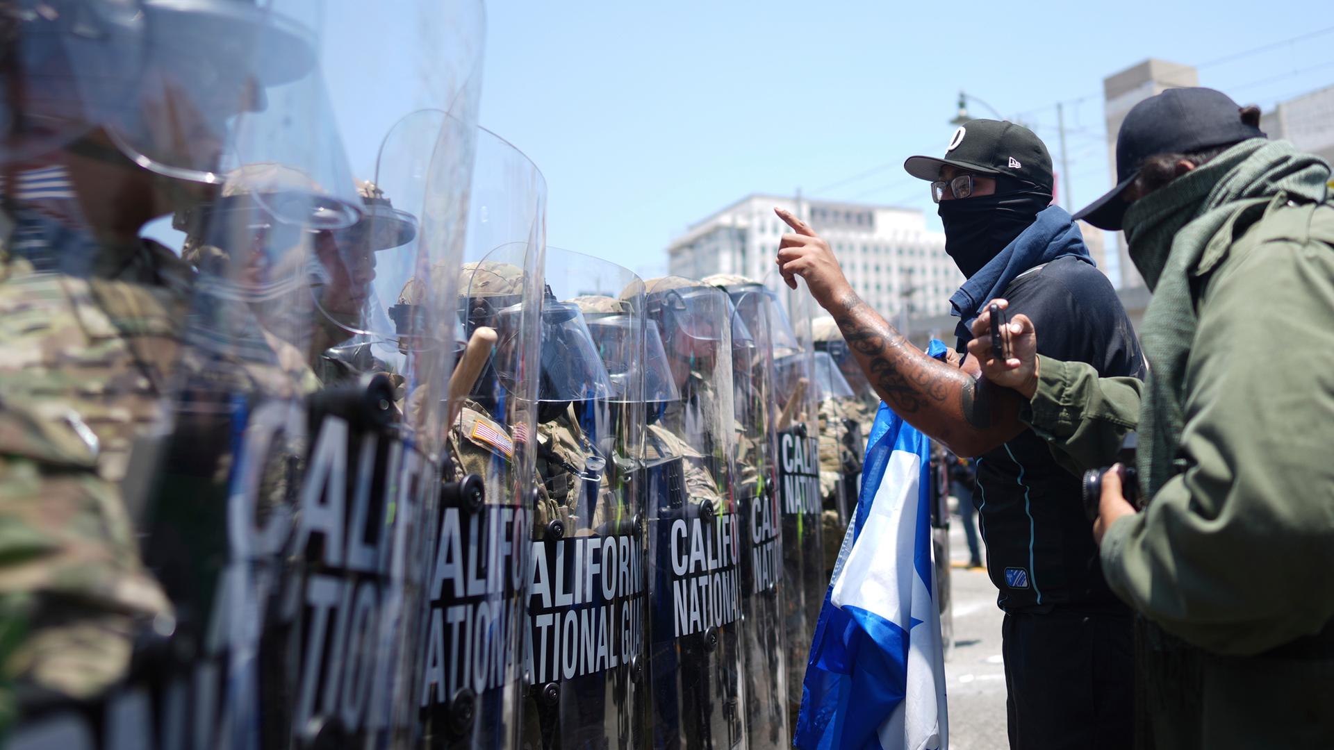 emonstranten stehen einer Reihe von US-Nationalgardisten an einem Bundesgefängnis in Los Angeles gegenüber. emonstranten stehen einer Reihe von US-Nationalgardisten an einem Bundesgefängnis in Los Angeles gegenüber.