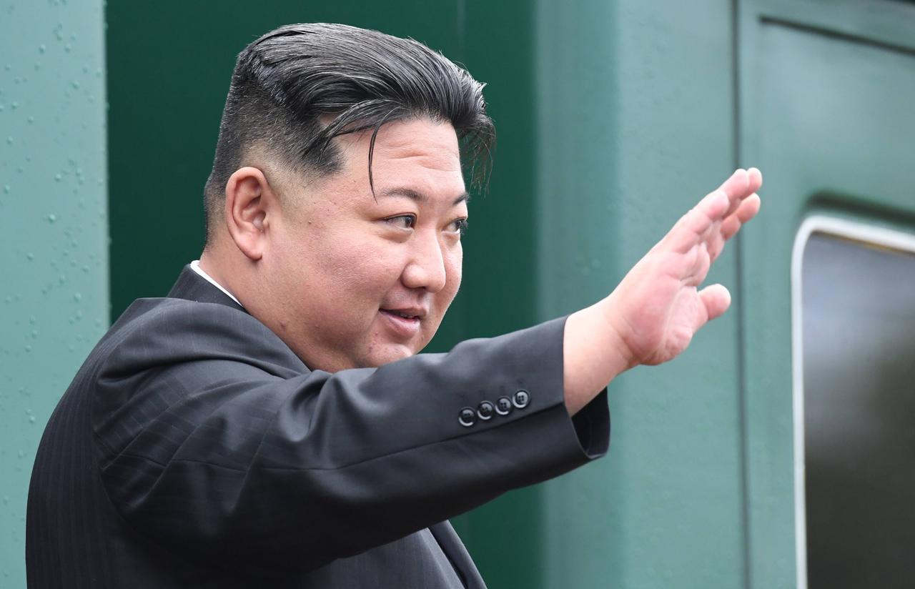 Kim Yong Un steht an einem Zug und winkt.