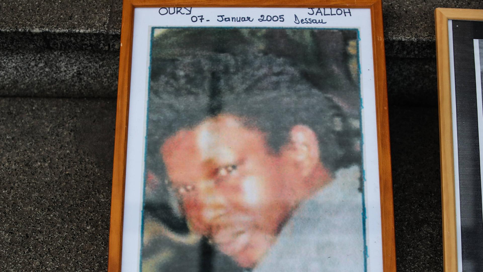 Die gerahmte Fotografie eines jungen, dunkelhäutigen Mannes. Das Foto trägt die Aufschrift "Oury Jalloh, 7. Januar 2005 Dessau".