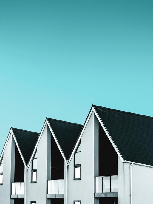 Die Dächer dreier moderner Häuser vor blauem Himmel