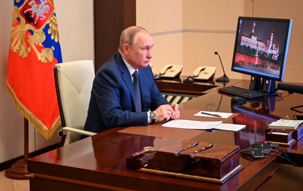 Russlands Präsident Putin sitzt vor einem Bildschirm an seinem Schreibtisch.