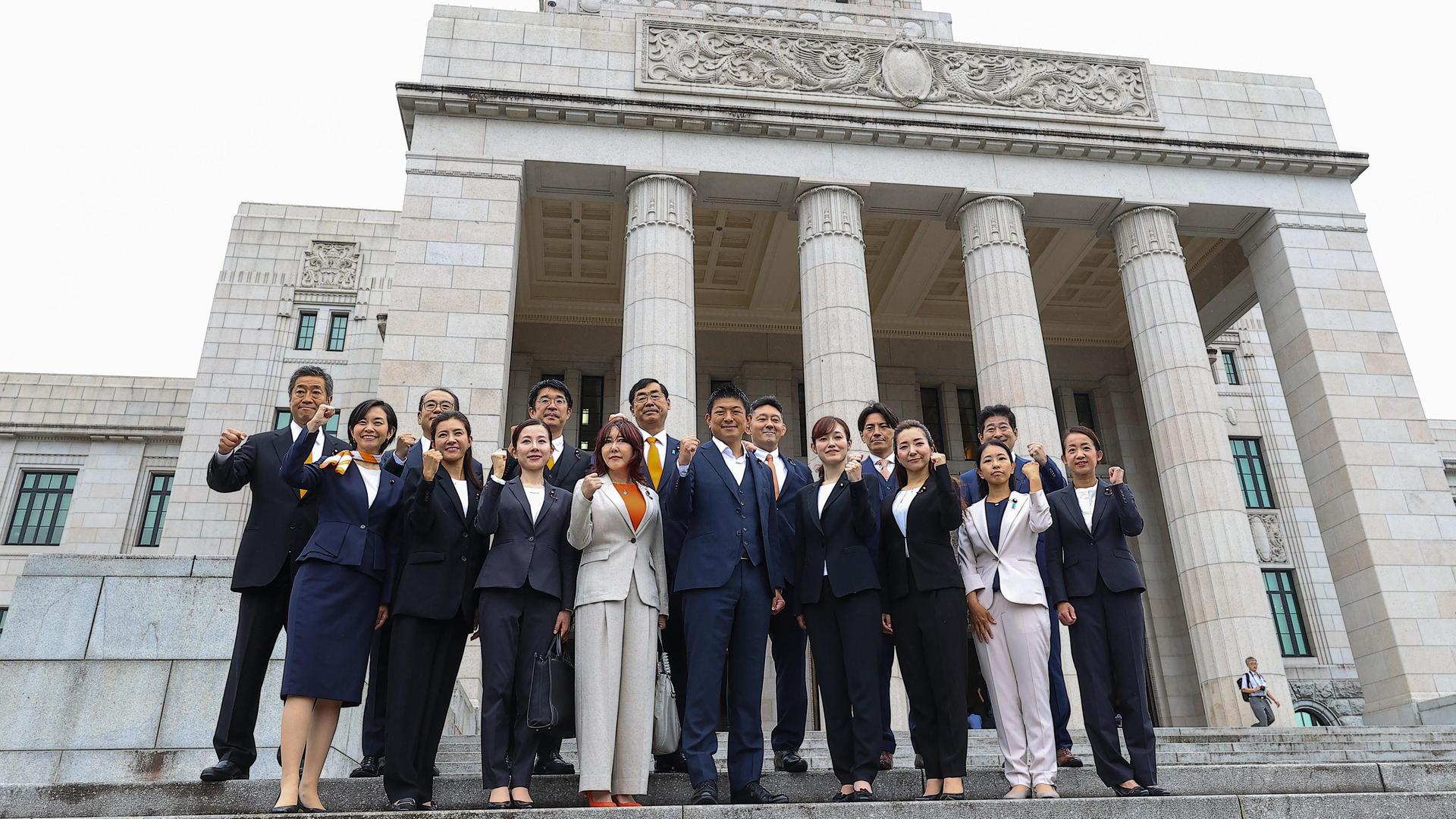Mitglieder der Partei Sanseito stehen vor dem Parlamentsgebäude in Tokio