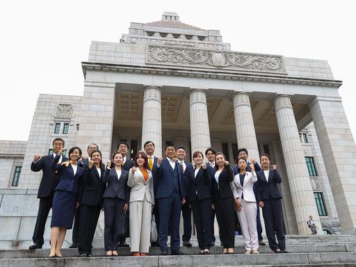 Mitglieder der Partei Sanseito stehen vor dem Parlamentsgebäude in Tokio Mitglieder der Partei Sanseito stehen vor dem Parlamentsgebäude in Tokio
