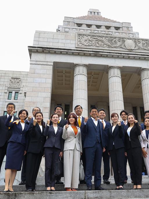 Mitglieder der Partei Sanseito stehen vor dem Parlamentsgebäude in Tokio