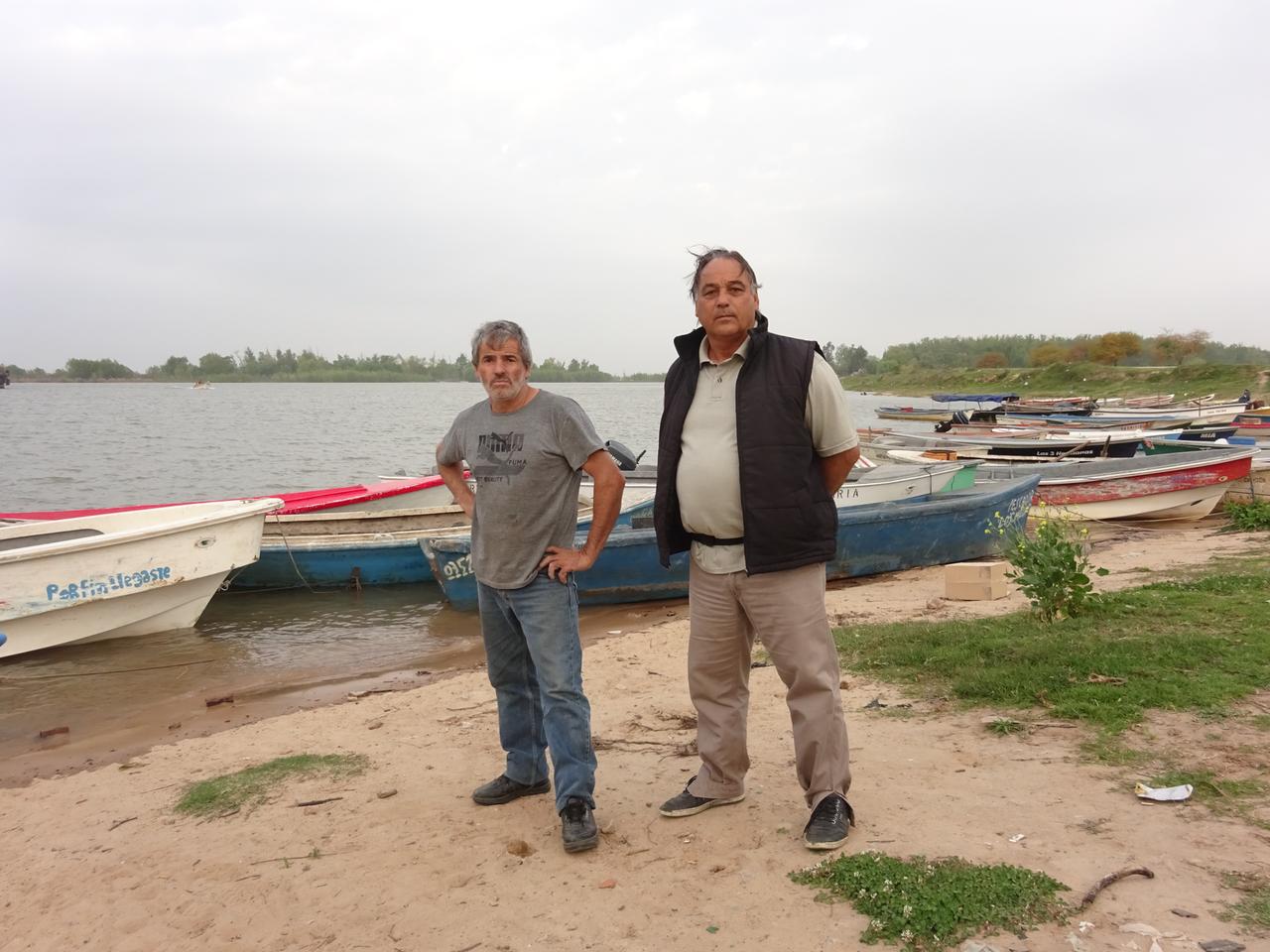 Zwei Männer vor Fischerbooten an einem Ufer