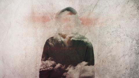 Diffuse Figur, deren Gesichtszüge und Teile des Körpers von Wolken verhangen sind