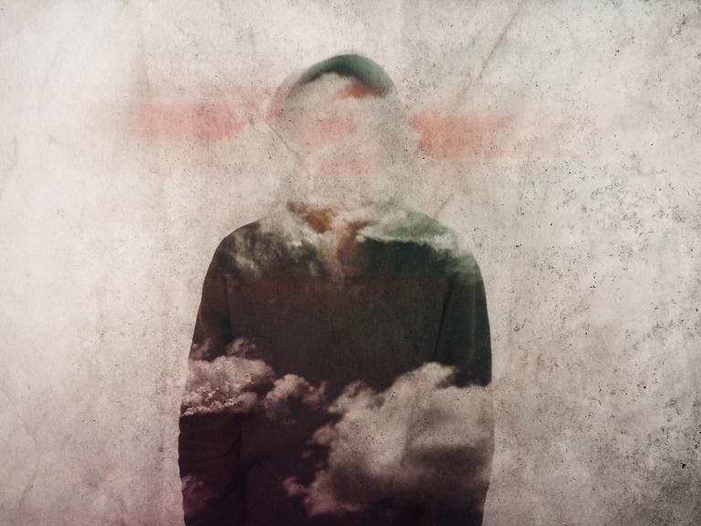 Diffuse Figur, deren Gesichtszüge und Teile des Körpers von Wolken verhangen sind