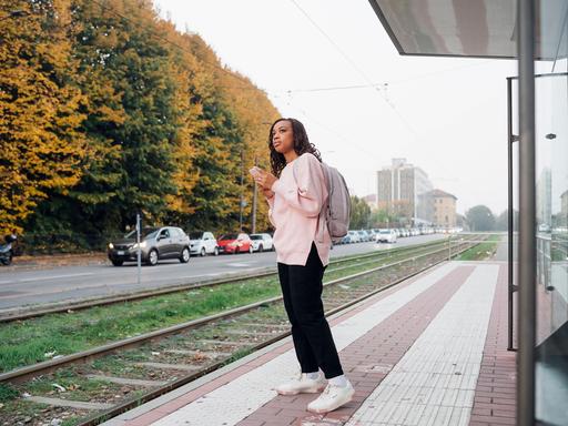 Eine Frau wartet am Bahnhofsgleis auf den Zug.