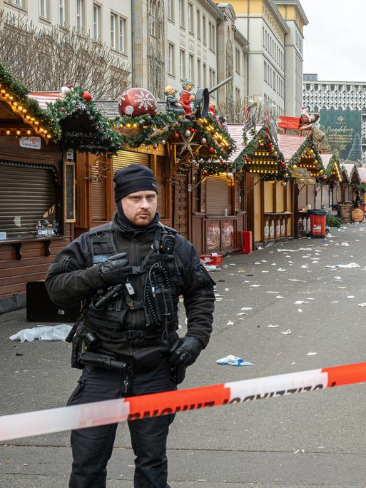 Polizisten stehen am Tag nach dem Anschlag hinter einem Absperrband vor dem Weihnachtsmarkt in Magdeburg.