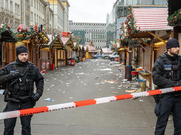 Polizisten stehen am Tag nach dem Anschlag hinter einem Absperrband vor dem Weihnachtsmarkt in Magdeburg.