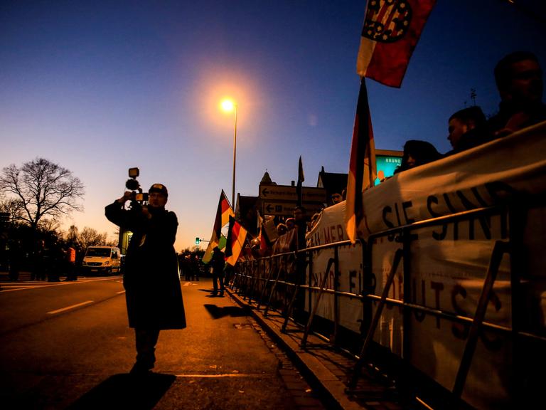 Rechtradikale protestieren am 16. November 2018 mit Bannern während eines Besuchs der damaligen Bundeskanzlerin Angela Merkel in Chemnitz. 