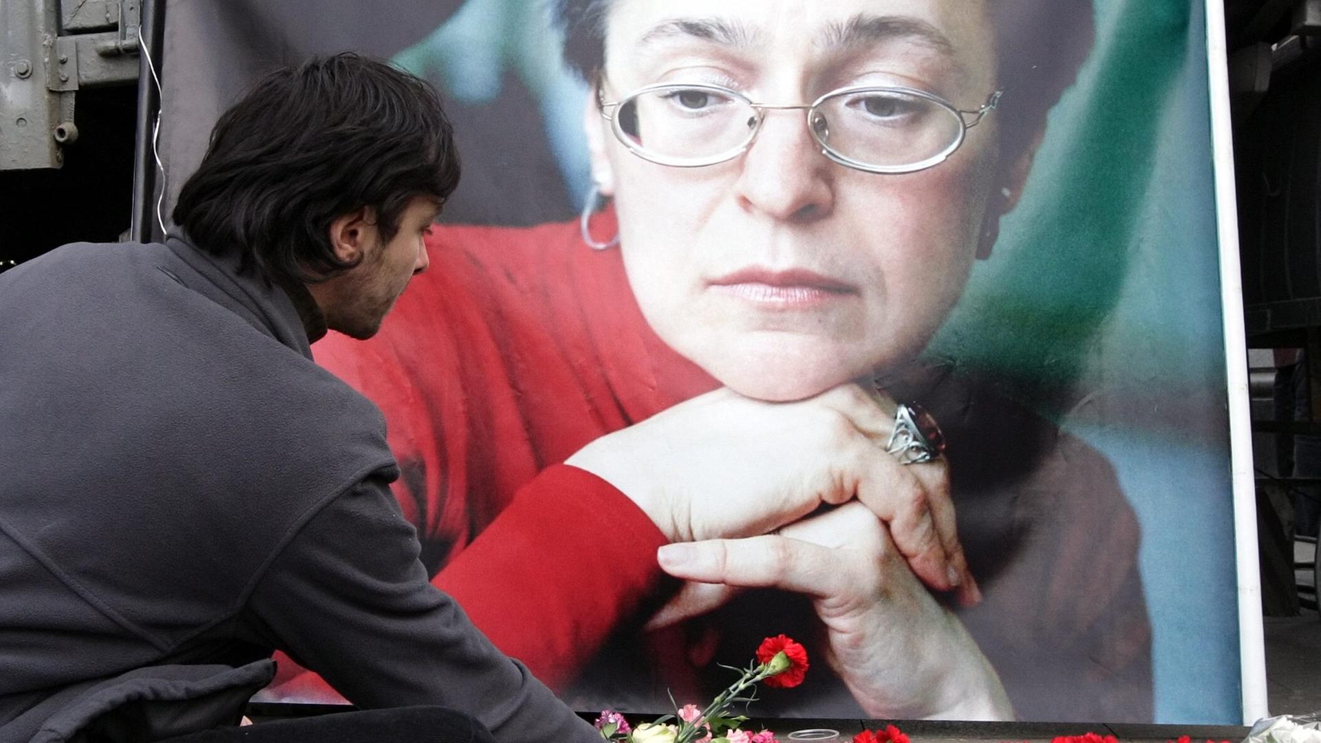 Ein Mann legt eine Blume vor einem Bild der ermordeten russischen Journalstin Anna Politkowskaja nieder.