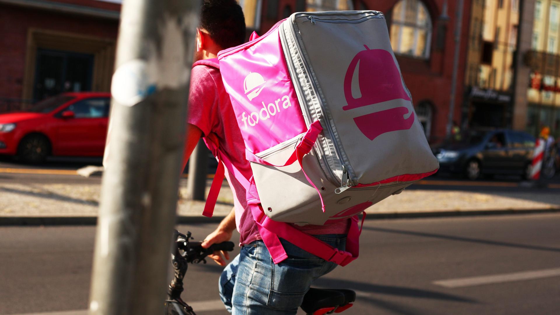 Ein Fahrer mit Rucksack von Foodora auf einem Fahrrad