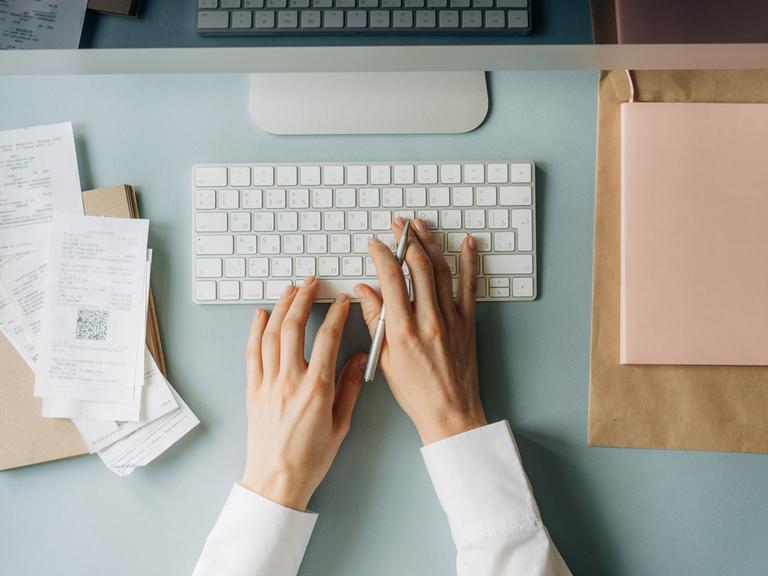 Weibliche Hand tippt auf Computer-Tastatur.