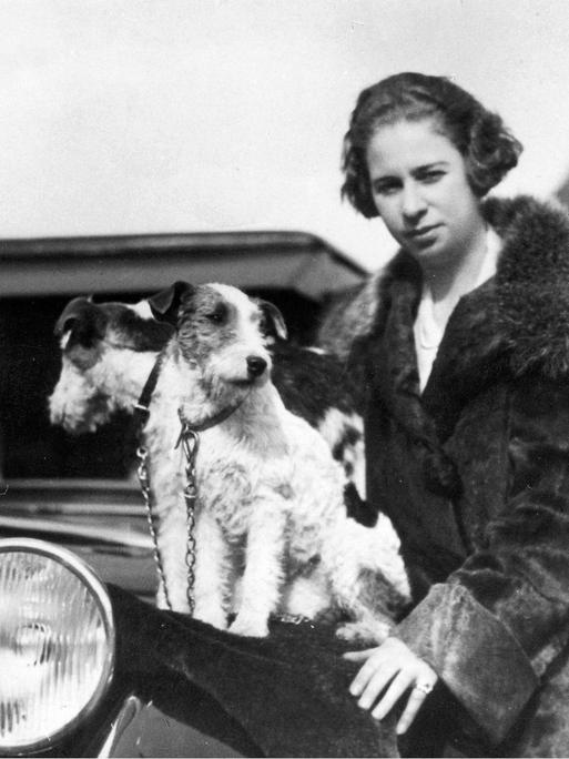 Historische schwarz-weiß Aufnahme zeigt die Rennfahrerin Clärenore Söderström-Stinnes im Jahr 1927 vor einem Automobil. 