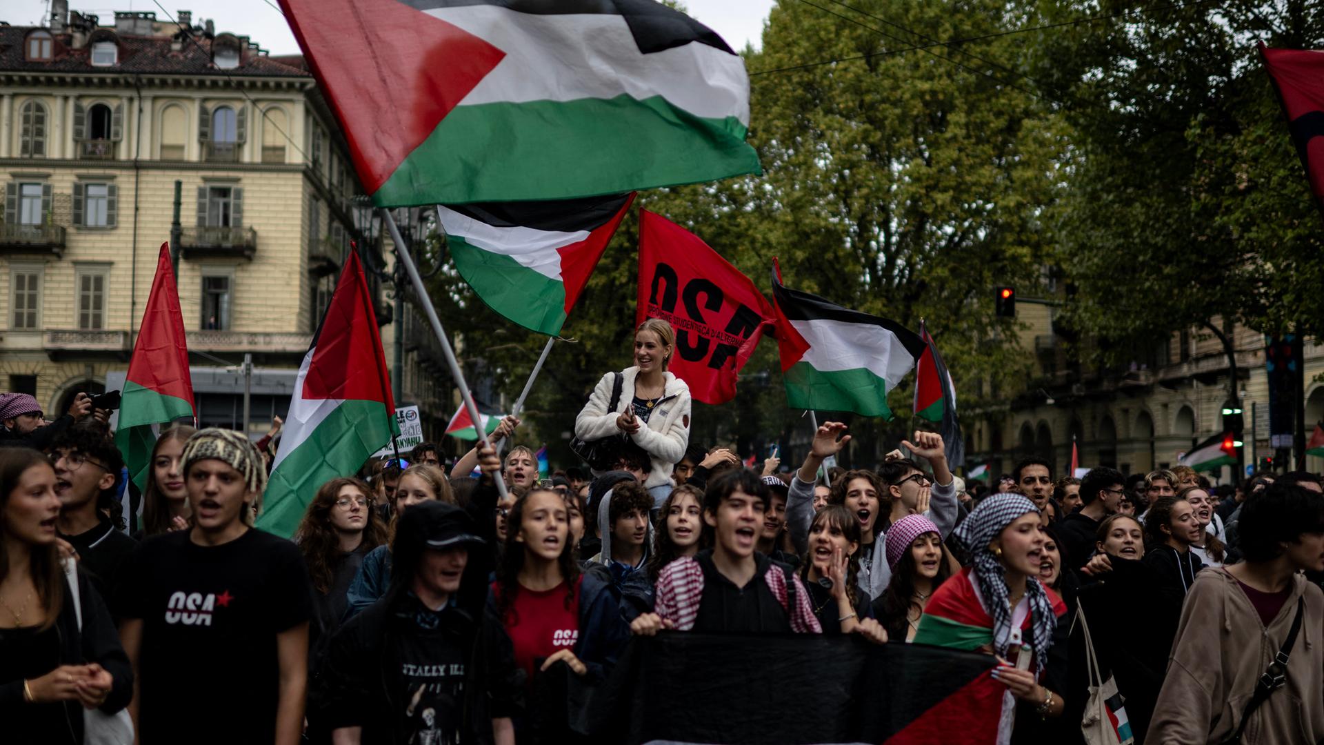 Studenten protestieren in Turin. Sie schwenken palästinensische Flaggen.
      