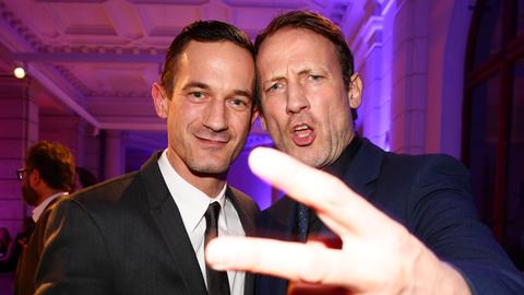 Soenke Moehring mit Bruder Wotan Wilke. Wotan Wilke Möhring streckt die Hand weit der Kamera entgegen und spreizt Zeige- und Mittelfinger in der Horizontalen.