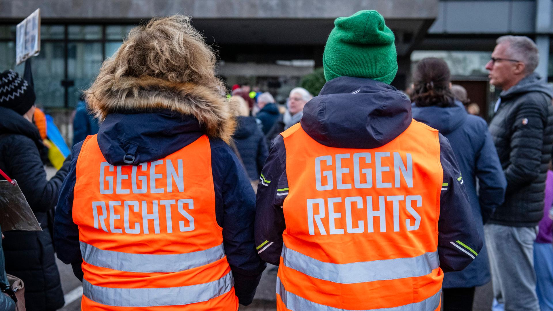 Teilnehmer einer Demonstration tragen orange Westen mit der Aufschrift "Gegen rechts"