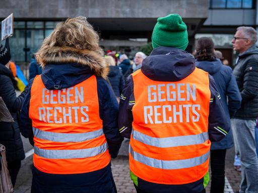 Teilnehmer einer Demonstration tragen orange Westen mit der Aufschrift "Gegen rechts"