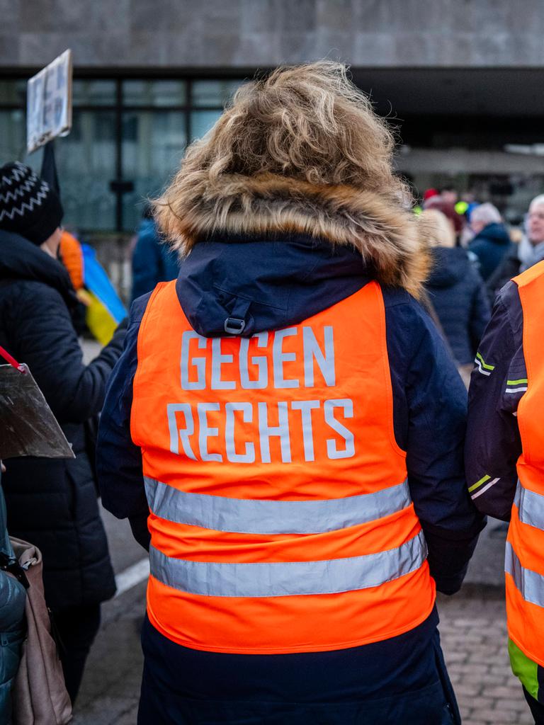 Teilnehmer einer Demonstration tragen orange Westen mit der Aufschrift "Gegen rechts"
