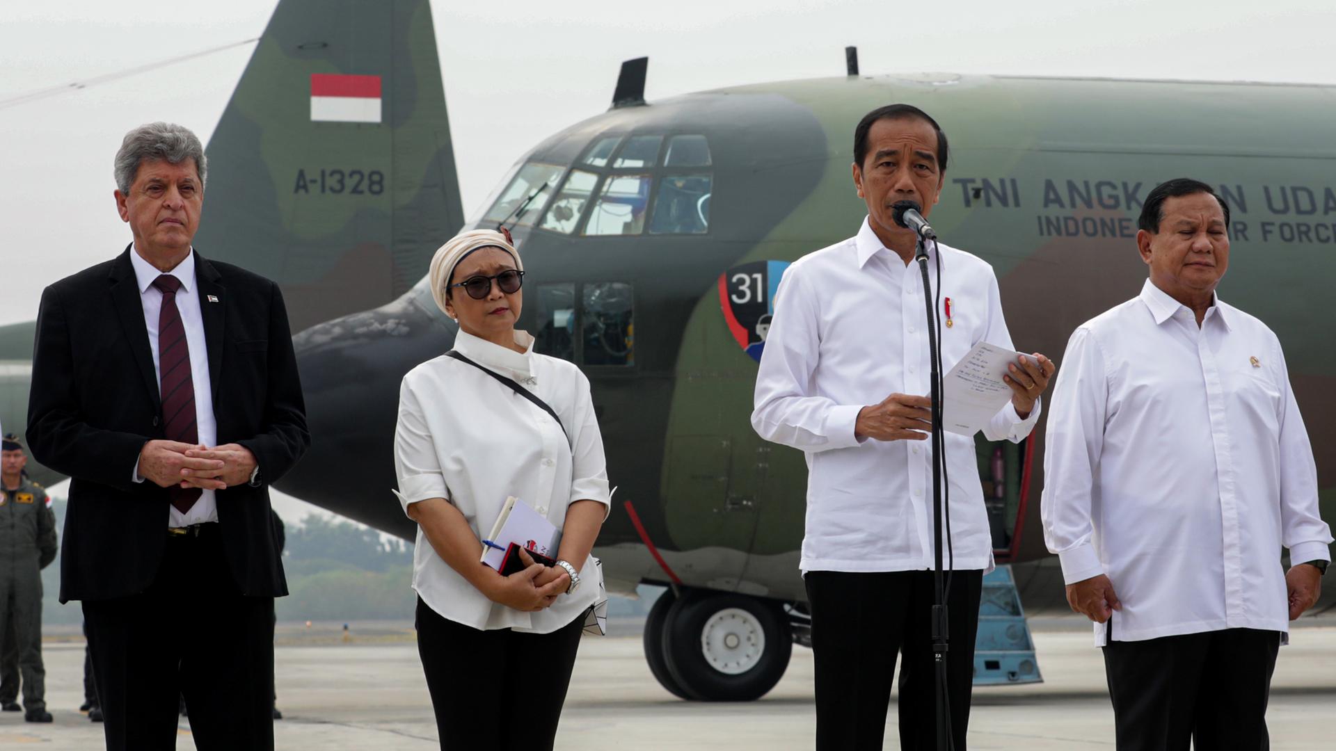 In Jakarat, Indonesien, steht Präsident Widodo (Zweiter von Rechts) mit drei weiteren Personen vor einem Transportflugzeug und spricht in ein Mikrofon. Aufnahme vom 4.11.2023.