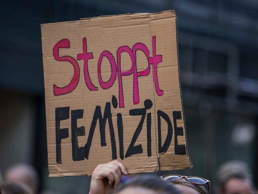 Eine Teilnehmerin einer Demonstration hält ein Schild mit der Aufschrift "Stoppt Femizide"