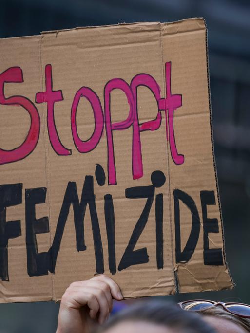Eine Teilnehmerin einer Demonstration hält ein Schild mit der Aufschrift "Stoppt Femizide"