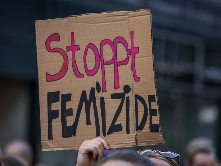 Eine Teilnehmerin einer Demonstration hält ein Schild mit der Aufschrift "Stoppt Femizide"