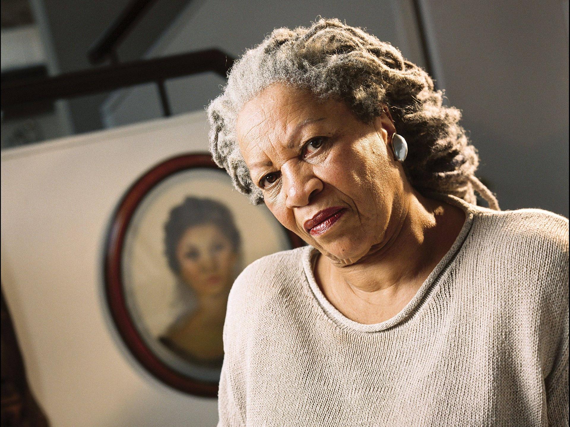 Toni Morrison posiert in ihrer New Yorker Wohnung für ein Foto. Hinter ihr hängt ein Porträt an der Wand, das sie als jüngere Frau zeigt,