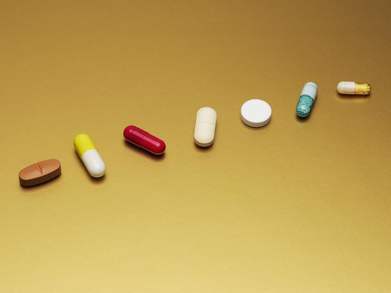 Stilleben: Arrangement verschiedene Medikamente Pillen und Kapseln auf gelbem Hintergrund 