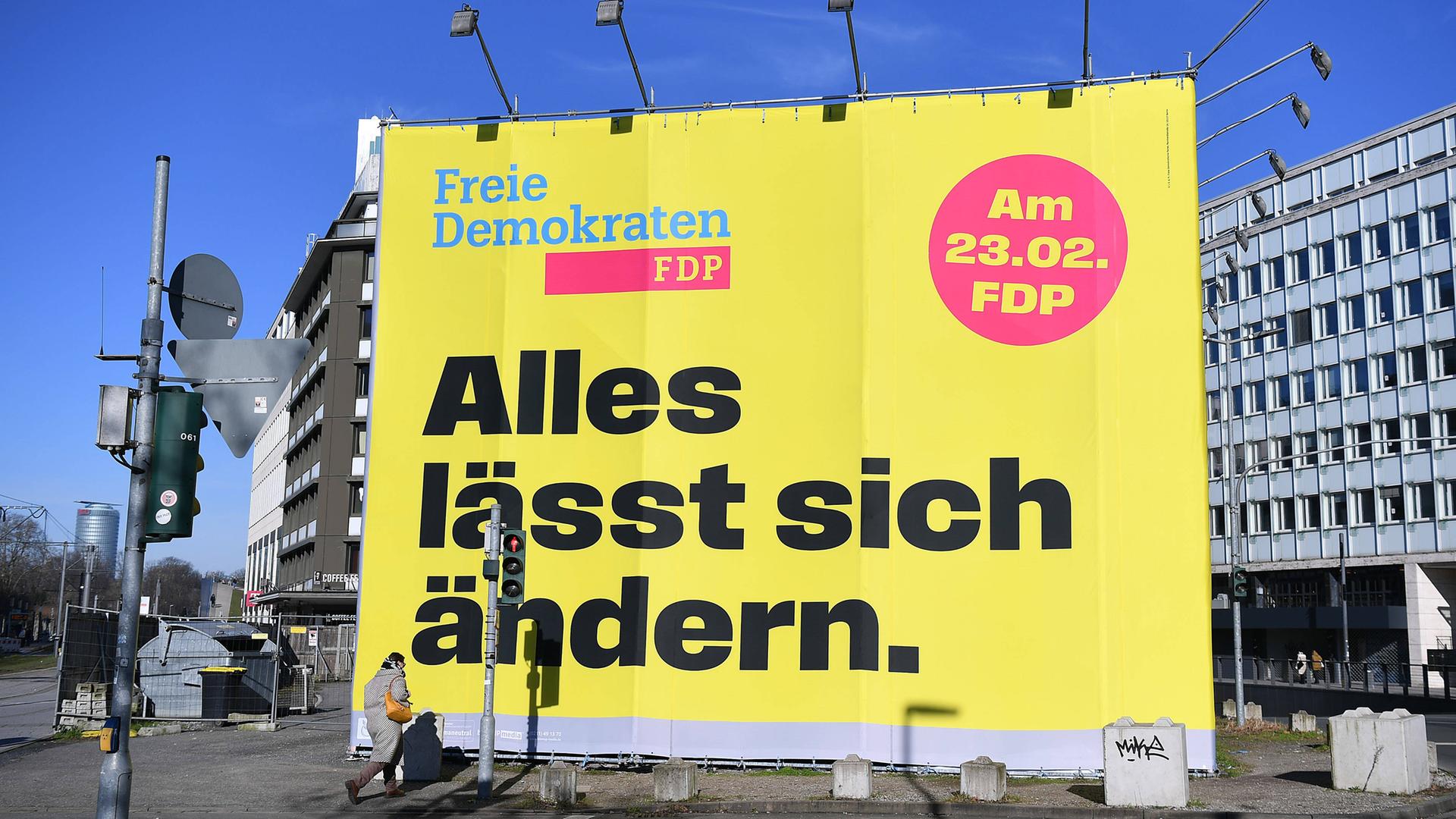 An einer Straße in Düsseldorf steht ein großes Wahlplakat der FDP zur Bundestagswahl 2025, auf dem in großen Buchstaben "Alles lässt sich ändern" steht.